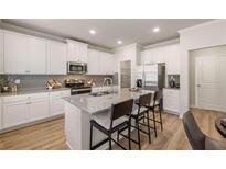 Bright kitchen features white cabinets, stainless steel appliances, granite countertops and seating at the kitchen island at 4549 Ajo Walk, Atlanta, GA 30331