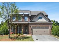 Charming two-story brick home with a well-maintained lawn, attached two car garage, and lovely landscaping at 3065 Arbor Song Ct, Cumming, GA 30041