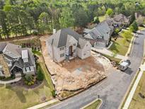 Spacious home construction with an unfinished yard, showcasing the neighborhood and lush surrounding greenery at 5694 Brendlynn Dr, Suwanee, GA 30024