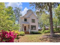 Charming two-story home with white siding, a red front door, and a beautifully landscaped front yard at 842 Bridgewater Sw St, Atlanta, GA 30310