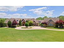 Grand home exterior featuring circular drive, mature landscaping, and stone accents at 2220 Peachtree Rd, Cumming, GA 30041