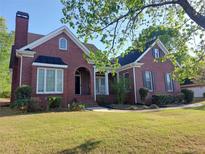Charming brick home featuring a well-maintained lawn and complemented by mature trees at 1272 Saxony Se Dr, Conyers, GA 30013