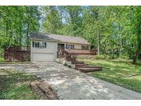 Charming home with a deck, featuring mature trees and a well-maintained front yard and an attached garage at 1373 Janice Sw Ct, Lilburn, GA 30047