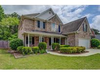 Charming brick two-story home with a covered front porch and beautifully landscaped front yard at 1670 Cooper Lakes Dr, Grayson, GA 30017