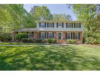 Charming two-story home with a brick facade, black shutters, and a well-manicured front lawn at 1569 Chateau Dr, Dunwoody, GA 30338