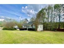 Charming single-story home features lush green lawn and mature trees under a partly cloudy sky at 25 Derby Dr, Hiram, GA 30141