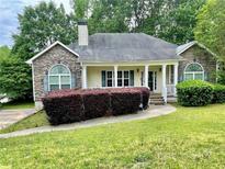 Charming single-story home featuring a stone facade, manicured lawn, and inviting front porch at 25 Derby Dr, Hiram, GA 30141