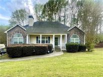 Charming home with stone accents, arched windows, covered porch, manicured lawn, and lush landscaping at 25 Derby Dr, Hiram, GA 30141