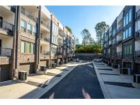 Modern townhome exteriors with brick accents, garages, and balconies under a clear blue sky at 383 Pratt Se Dr # 506, Atlanta, GA 30315