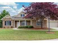 Charming brick home featuring a well-manicured lawn, mature tree, and an attached two-car garage at 1640 Arbor Green Nw Ct # 1102, Kennesaw, GA 30152