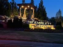 Well-lit Bramblett Grove entrance sign with stone waterfall feature and manicured landscaping at 4685 Trefoil Path, Cumming, GA 30040