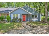 Charming blue home features a bright red front door, large window, and well-maintained lawn at 5126 Farm Place Ne Dr, Woodstock, GA 30188