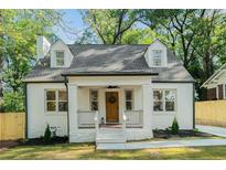 Charming home with a white brick exterior, dormer windows, wood door and welcoming front porch at 1555 Olympian Sw Way, Atlanta, GA 30310
