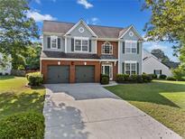 Charming two-story home with brick and gray siding, well-manicured lawn, and a two-car garage at 3317 Ridgemill Cir, Dacula, GA 30019