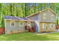 Charming two-story home with stone accents and a well-maintained lawn, surrounded by lush greenery at 484 Aberdeen Dr, Stonecrest, GA 30083