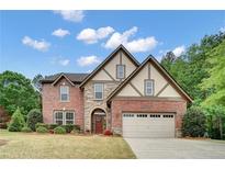 Charming two-story brick home with stone accents and a well-manicured lawn under a sunny sky at 3215 Trowbridge Dr, Cumming, GA 30040