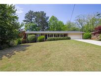 Charming brick ranch home with manicured lawn, a front porch, an attached two-car garage and mature trees at 4350 Bonaparte Dr, Tucker, GA 30084