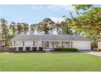 Charming white brick ranch-style home with a well-manicured lawn and mature trees at 1834 Kimberly Sw Dr, Marietta, GA 30008