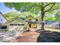 Charming home featuring a brick walkway, mature trees, a front porch with seating, and an attached garage at 4157 Town Branch Ct Sw, Covington, GA 30014