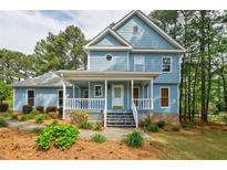 Charming two-story home with a covered front porch, manicured landscaping, and light blue siding at 1697 Ramblewood Way, Snellville, GA 30078
