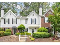 Charming townhome featuring a well-manicured lawn, complemented by a mix of brick and white wood facade and black shutters at 3065 Camden Way, Alpharetta, GA 30005