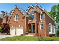 Charming two-story red brick home featuring a two-car garage and manicured lawn at 1228 Dunwoody Walk, Atlanta, GA 30338