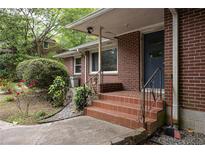 Brick home entrance featuring tiled steps, black railing, and a tidy front yard landscape with budding red flowers at 2383 N Decatur Rd, Decatur, GA 30033