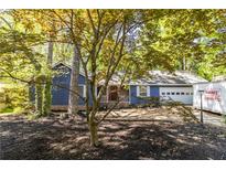 Charming blue home featuring a well-manicured front yard and an attached garage at 5272 Cumberland Way, Stone Mountain, GA 30087