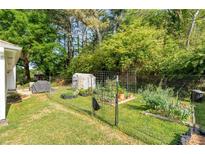 Spacious backyard featuring a lush garden, greenhouse, and secure fencing for outdoor enjoyment at 2014 Anchor Way, Buford, GA 30518