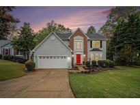 Charming two-story home with a well-manicured lawn, attached garage, and a welcoming red front door at 4272 Glenlake Nw Dr, Kennesaw, GA 30144