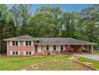 Charming brick home with white shutters, complemented by a spacious carport and lush front yard at 851 Rockbridge Sw Rd, Lilburn, GA 30047