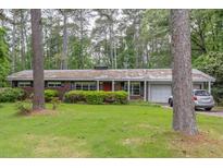 Charming single-story home with lush front lawn and mature trees in a peaceful setting at 881 Rockbridge Sw Rd, Lilburn, GA 30047