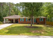 Charming brick home with turquoise shutters, a covered carport, and mature trees in the front yard at 3761 Lindley Cir, Powder Springs, GA 30127