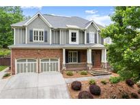 Beautiful two-story home with a brick and gray facade, two-car garage, and a welcoming front porch at 1286 Whisper Cove Dr, Buford, GA 30518