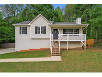Charming home featuring a cozy front porch, neutral siding, green lawn, and mature trees at 148 White Pine Ln, Temple, GA 30179