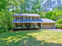 Charming two-story home with a lush front lawn and mature trees, featuring a welcoming covered porch at 351 Ridgewater Dr, Marietta, GA 30068