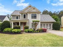 Charming two-story home with gray siding, a landscaped yard, and an attached two-car garage at 135 Haleys Cir, Woodstock, GA 30188