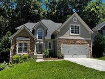 Charming two-story home featuring a stone facade, well-manicured lawn, and an attached two-car garage at 3045 Wyntree Dr, Peachtree Corners, GA 30071
