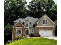 Charming two-story home with a stone and stucco facade, lush lawn, and attached two car garage at 3045 Wyntree Dr, Peachtree Corners, GA 30071