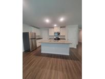 Modern kitchen features stainless steel appliances and a large island with a granite countertop, and wood floors at 558 Fairview Oak Place, Dallas, GA 30157