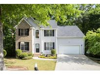 Charming two-story home with a brick facade, light gray siding, well-manicured lawn and mature trees at 2620 Nesbitt Crossing Way, Duluth, GA 30096