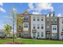 Charming townhome exterior with brick and white facade, complemented by a lush green lawn and tree at 3130 Bennett Creek Ln, Suwanee, GA 30024