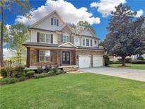 Charming two-story home featuring stone accents, a well-manicured lawn, and a welcoming two-car garage at 5106 Davis Love Dr, Cumming, GA 30041