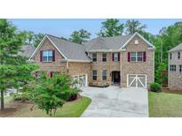 Lovely two-story brick home with well-manicured lawn and a spacious three-car garage and inviting burgundy shutters at 4395 Wildbrooke Pkwy, Cumming, GA 30041