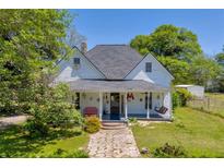 Charming two-story home featuring a welcoming front porch with swing, stone pathway, and well-maintained lawn at 215 Fair St, Loganville, GA 30052
