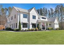 Charming two-story white home featuring black-framed windows, landscaped yard, and American flag at 1455 Rucker Cir, Woodstock, GA 30188