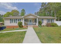 Charming single-story home features a covered porch with swing, classic siding, and lush landscaping at 5185 Twin Oak Ne Dr, Woodstock, GA 30188