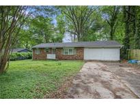 Charming single-story brick home featuring a two-car garage and a lawn partially covered in greenery at 2412 Forrest Park Se Rd, Atlanta, GA 30315