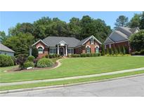 Charming red brick home featuring a well-manicured lawn, mature landscaping, and a welcoming front entrance at 4019 Hickory Fairway Dr, Woodstock, GA 30188