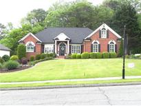 Charming brick home with a beautifully landscaped front yard and lush green lawn at 4019 Hickory Fairway Dr, Woodstock, GA 30188